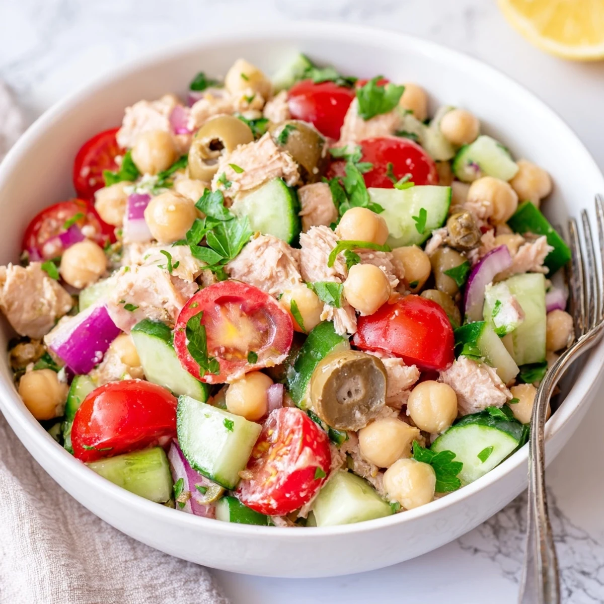 Mediterranean-style tuna and garbanzo bean salad featuring cherry tomatoes, cucumber, and Kalamata olives in olive oil
