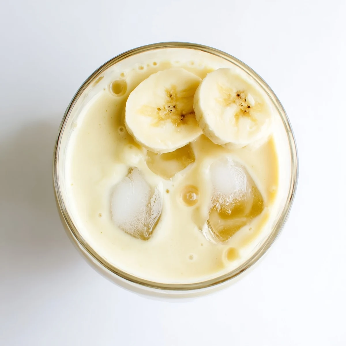 Thick protein-packed Greek yogurt banana smoothie blended with ice and honey drizzle