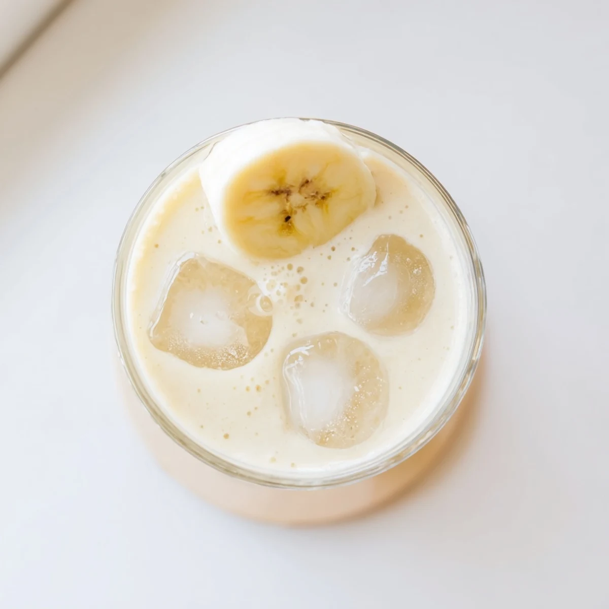 Creamy Greek yogurt banana smoothie topped with fresh banana slices in a glass
