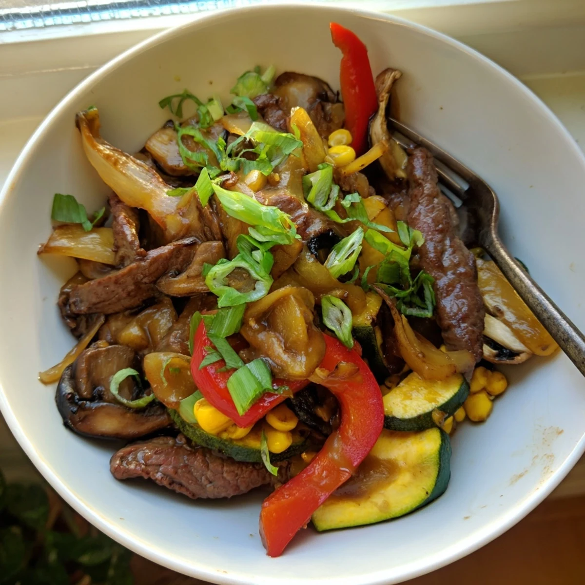 Rustic cowboy stir fry features caramelized steak onions and peppers served in a cast iron skillet