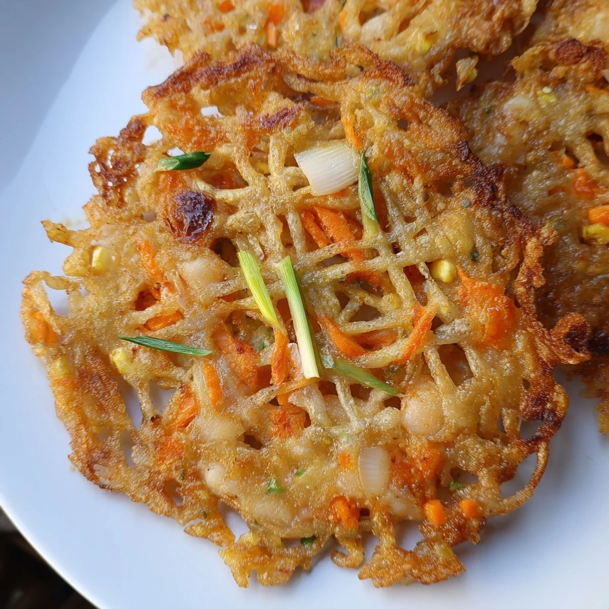 Golden crispy Ukoy Filipino shrimp fritters served with vinegar garlic dipping sauce on a white plate