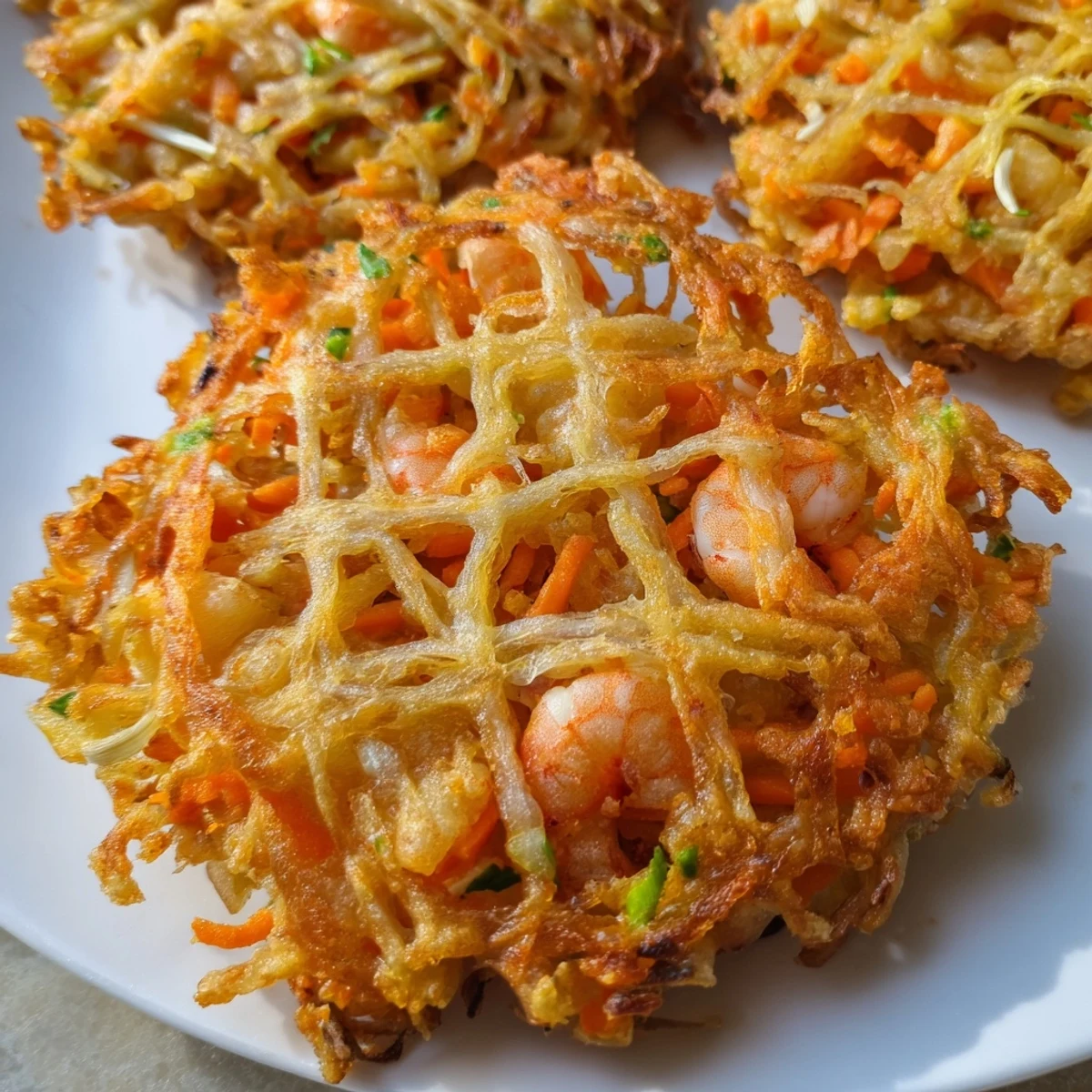 Close-up of Ukoy Filipino shrimp fritters showcasing whole shrimp and julienned vegetables in crunchy batter
