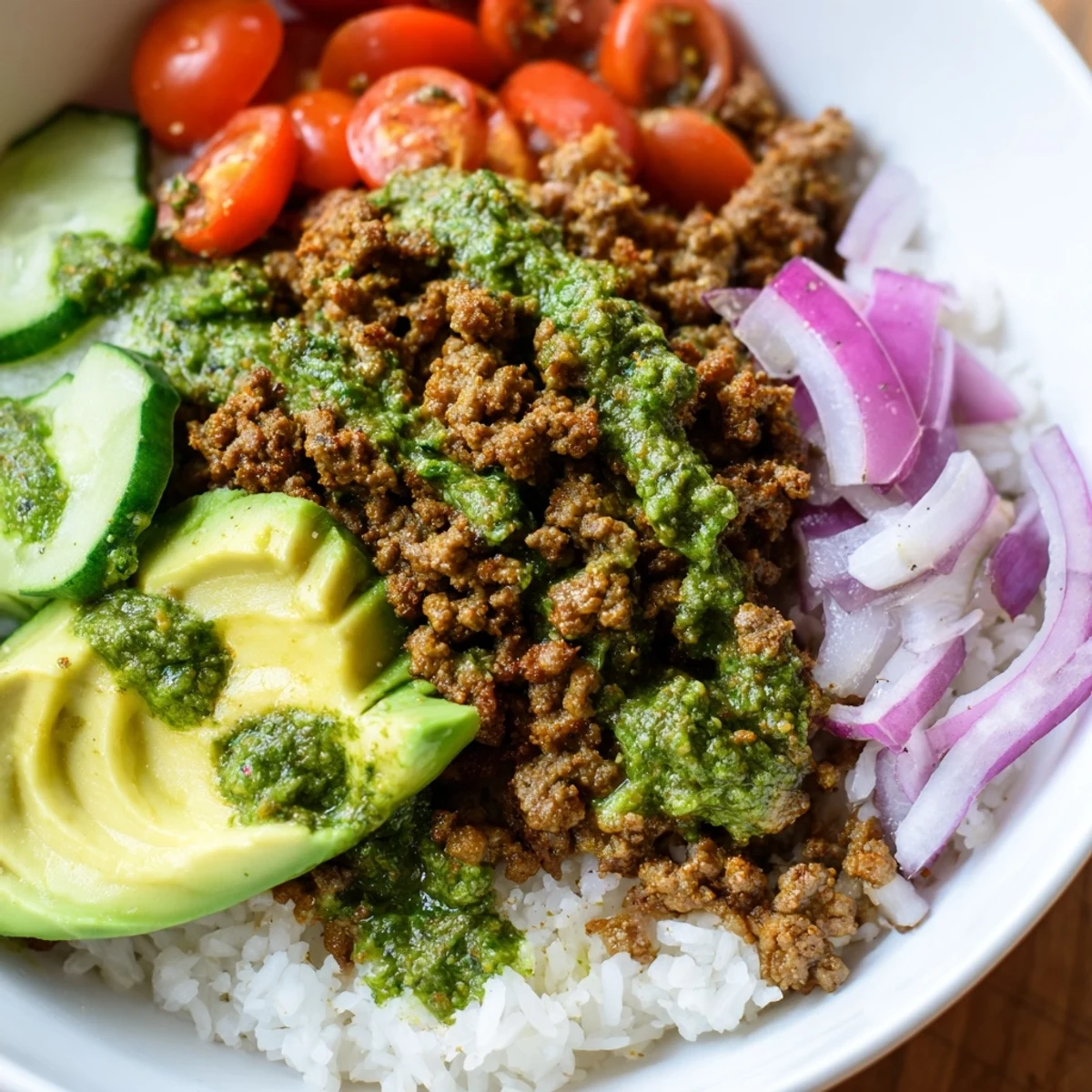 Chimichurri ground beef bowls with fresh vegetables and bright green herb sauce over fluffy white rice