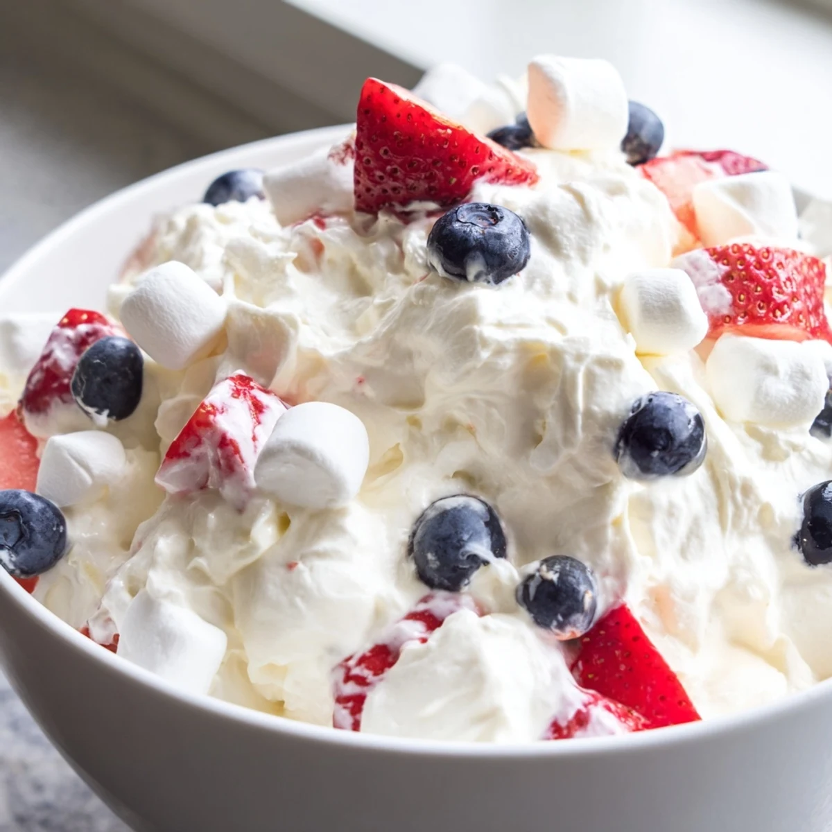 Vibrant strawberries and blueberries folded into a luscious red white blue cheesecake salad