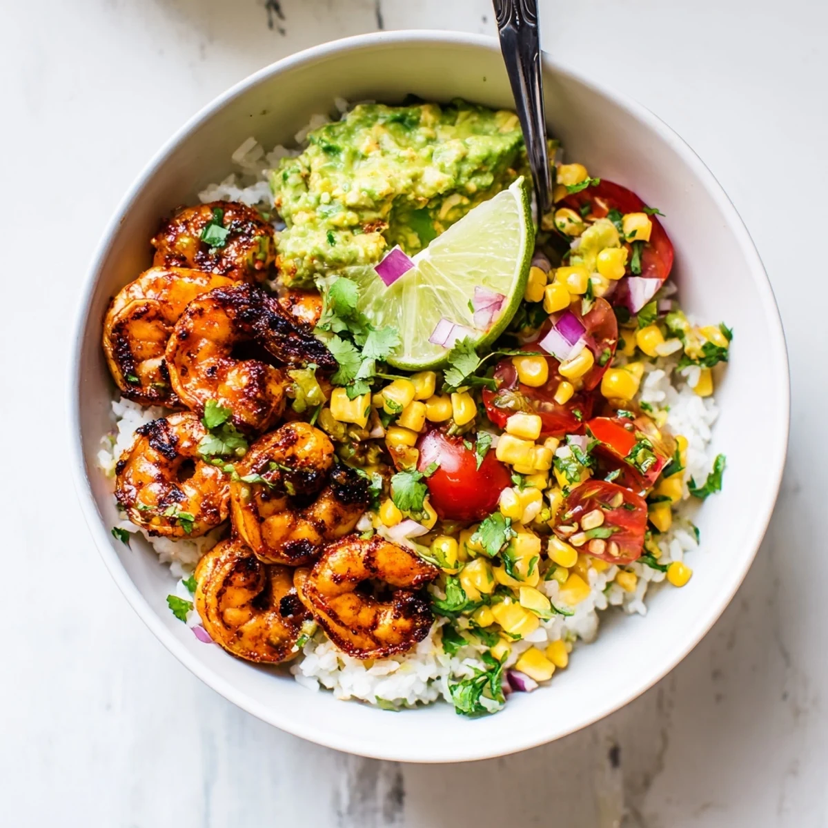 Smoky grilled shrimp bowl topped with bright avocado corn salsa and lime