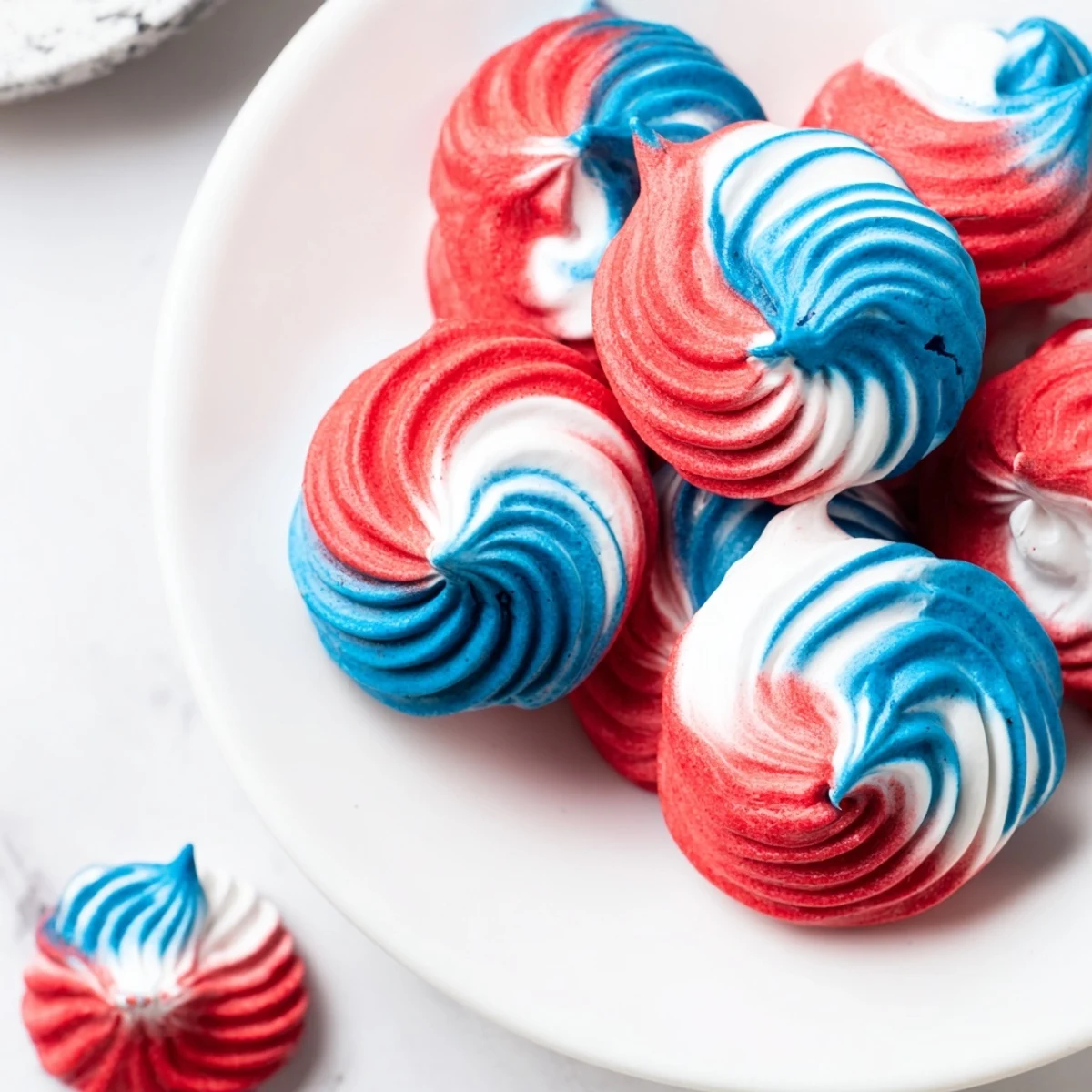 Delicate, crisp Patriotic Meringue Kisses swirled red, white, and blue on parchment