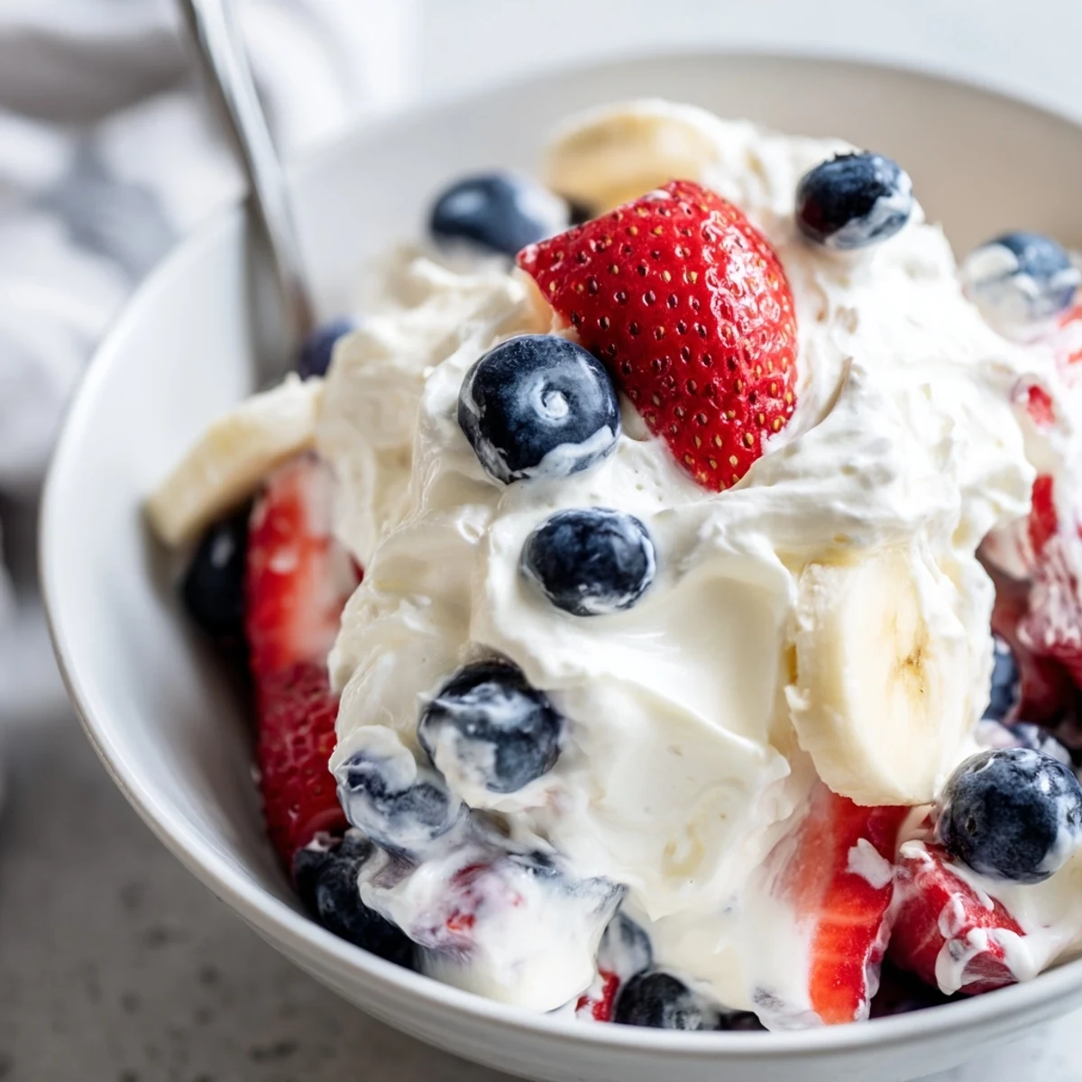 A festive Red White And Blue Cheesecake Salad layered with strawberries, blueberries, bananas.