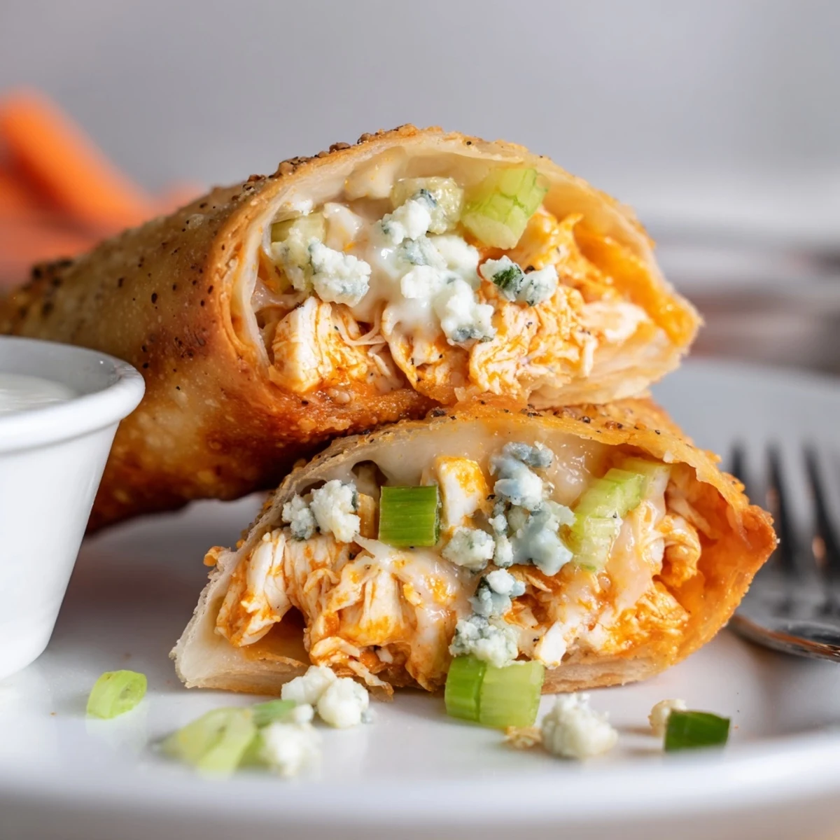 Crispy Buffalo Chicken Egg Rolls piled on plate with ranch dip  
