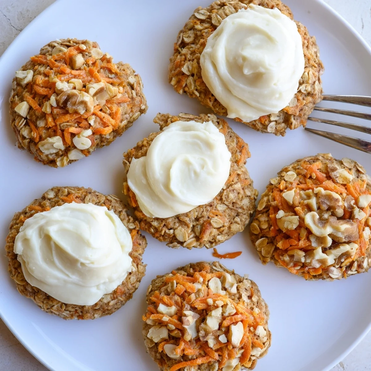Close-up of spiced carrot cake cookies topped with creamy white cream cheese frosting swirl