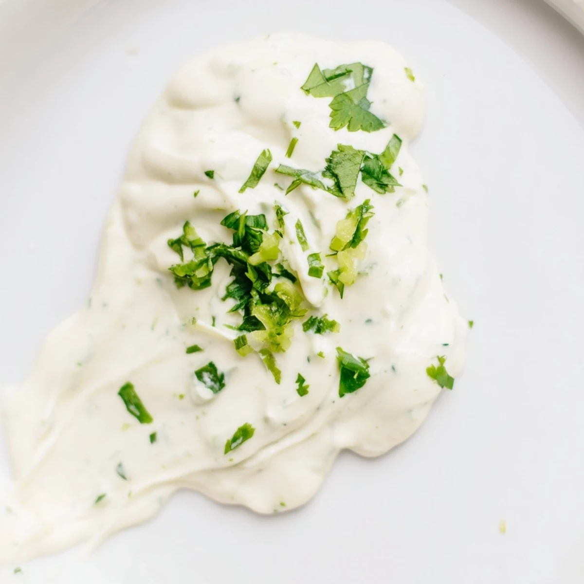 Creamy homemade Mexican white sauce in a white serving bowl garnished with fresh green cilantro leaves