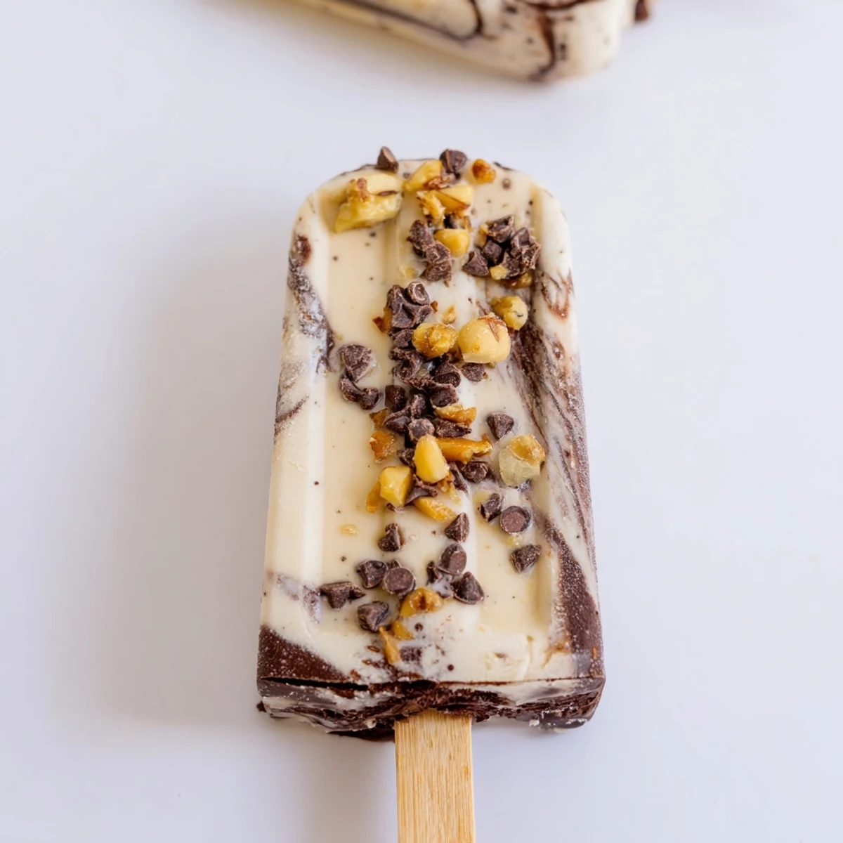 Decadent chocolate swirled banana bliss popsicles garnished with mini chocolate chips on a hot summer day