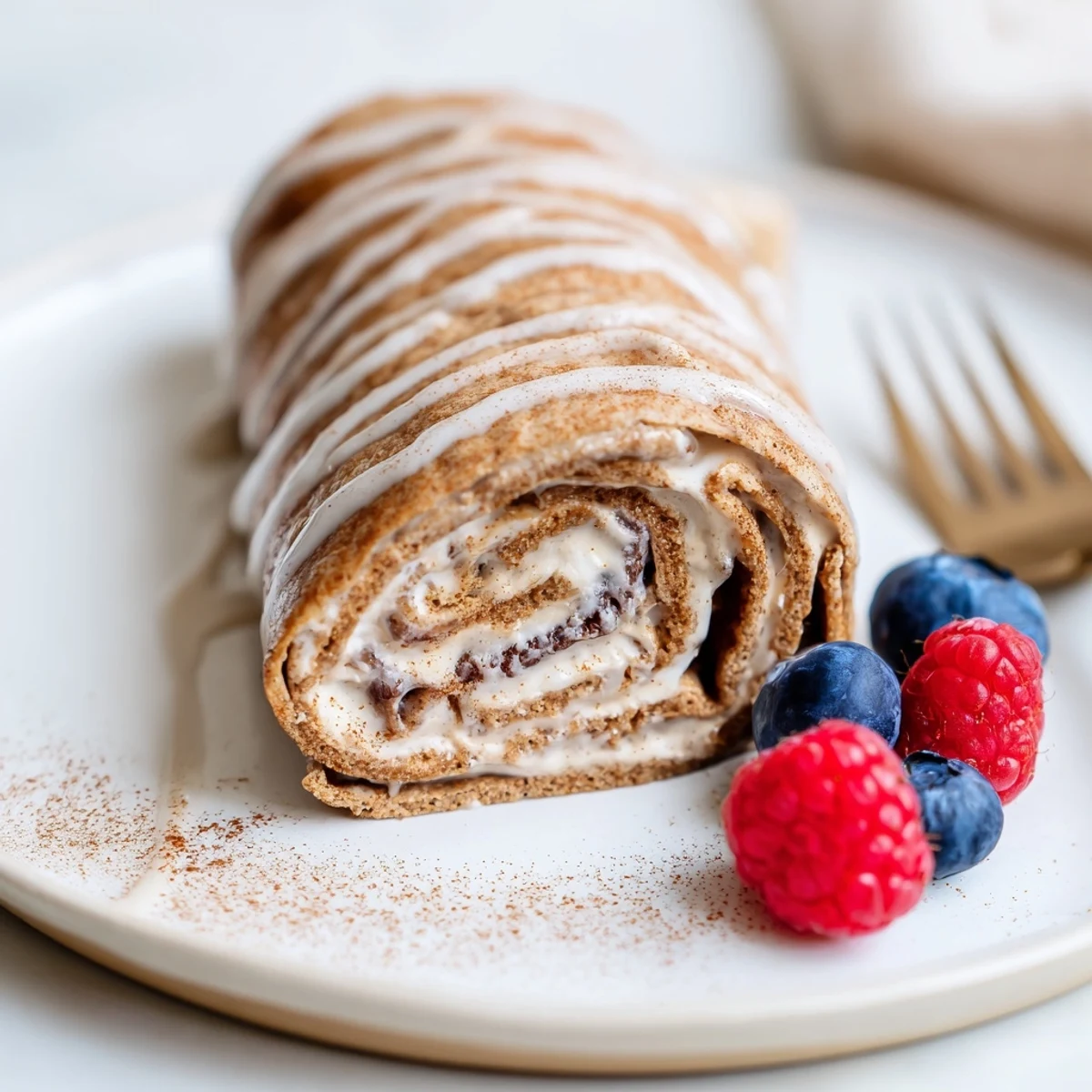 Warm, rolled Cinnamon Roll Protein Crepes Recipe with creamy cinnamon swirl inside