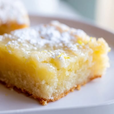 Creamy Lemon Gooey Butter Cake sliced into generous squares with a bright citrus glaze topping