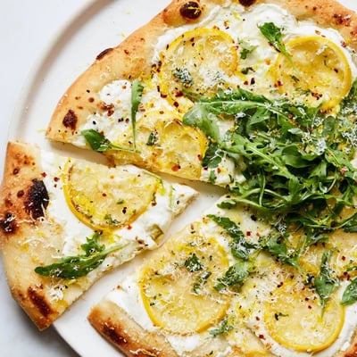 Warm slice of Zesty Summer Lemon Pizza topped with creamy cheese and basil